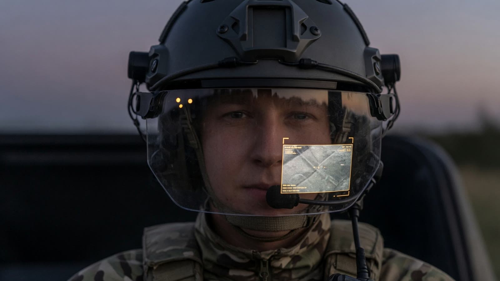 Operator in a vehicle wearing a communications helmet with a minimal visor overlay. Conceptual.